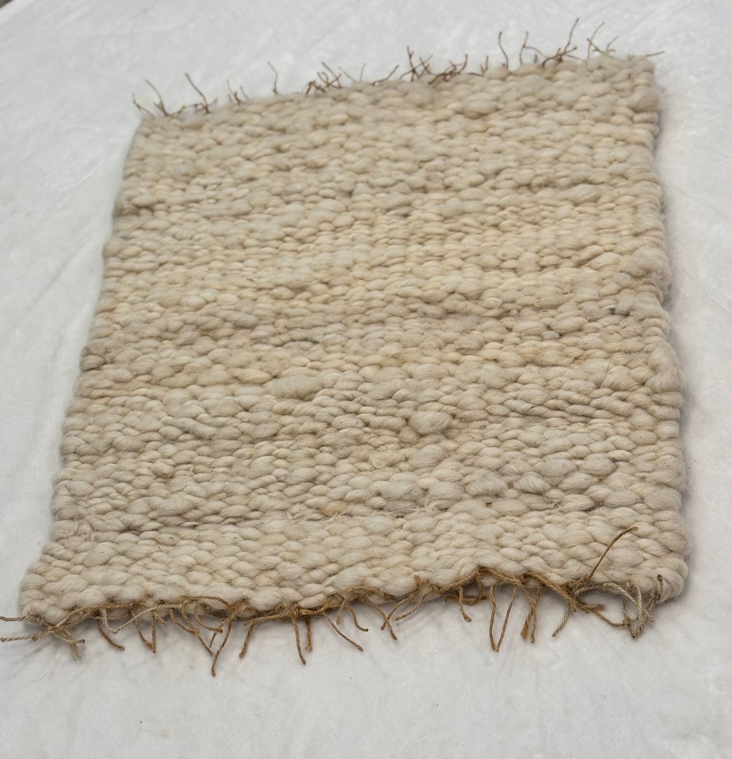This beautiful hand woven, off white, sheep wool rug is made from 100% sheep wool grown right here at Wild Daisy Homestead.
The warp and trim are made with 100% natural jute string. Created on a peg loom this 23X26 rug is tightly woven together. When removed, the finishing touches by tying the trim and hand stitching of the 100% leather tag attached, complete the project.