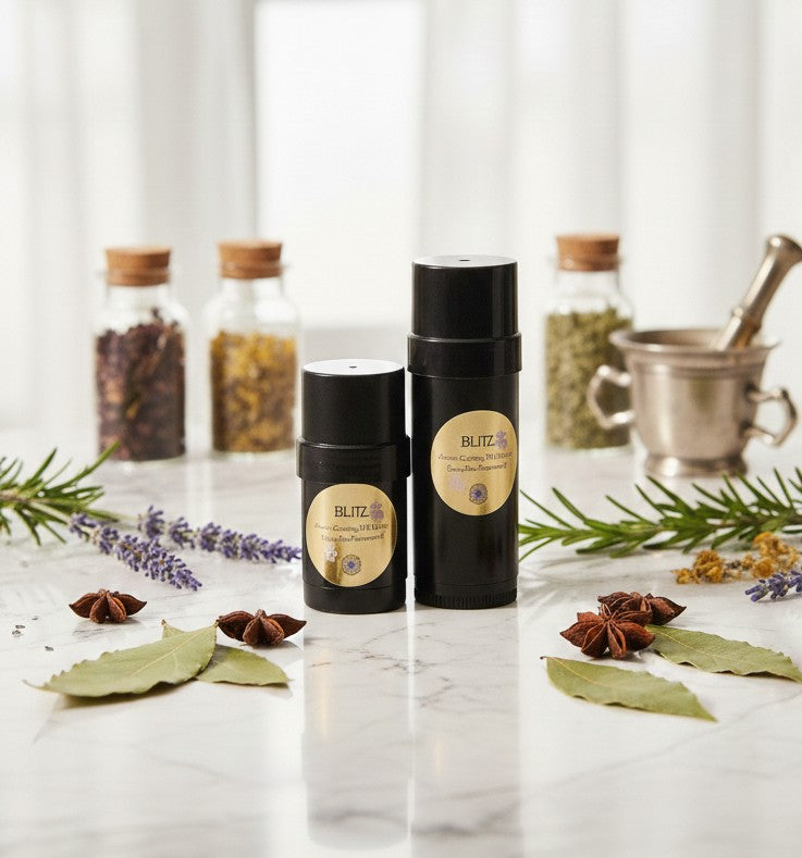 "A lifestyle display of Wild Daisy Homestead Blitz Salve, featuring the 1 oz Mini Twister and the 2.0 oz large Twister Stick side-by-side on a marble surface with fresh apothecary herbs."