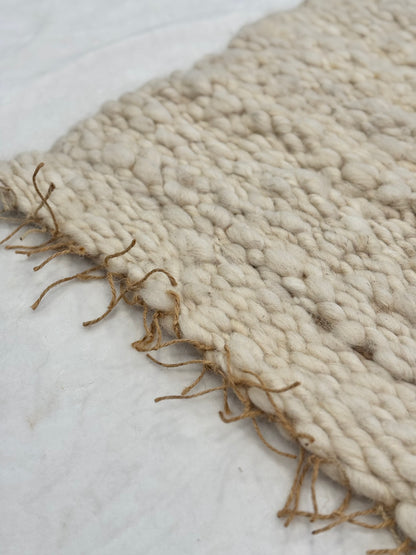 This beautiful hand woven, off white, sheep wool rug is made from 100% sheep wool grown right here at Wild Daisy Homestead.   
The warp and trim are made with 100% natural jute string.  Created on a peg loom this 23X26 rug is tightly woven together. When removed,  the finishing touches by tying the trim and hand stitching of the 100% leather tag attached, complete the project.  
