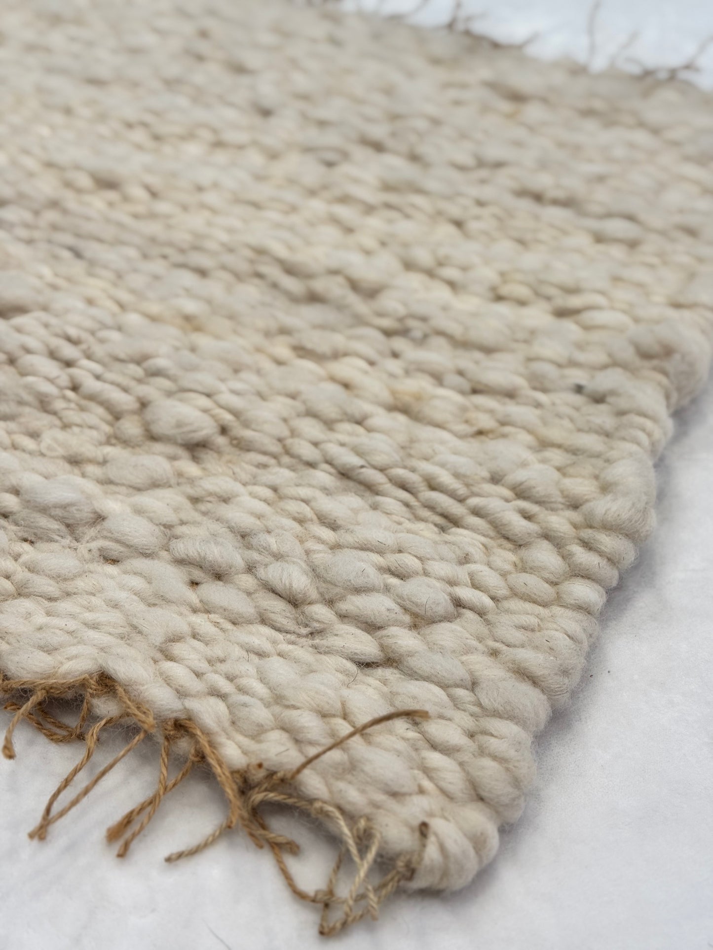 This beautiful hand woven, off white, sheep wool rug is made from 100% sheep wool grown right here at Wild Daisy Homestead.   
The warp and trim are made with 100% natural jute string.  Created on a peg loom this 23X26 rug is tightly woven together. When removed,  the finishing touches by tying the trim and hand stitching of the 100% leather tag attached, complete the project.  