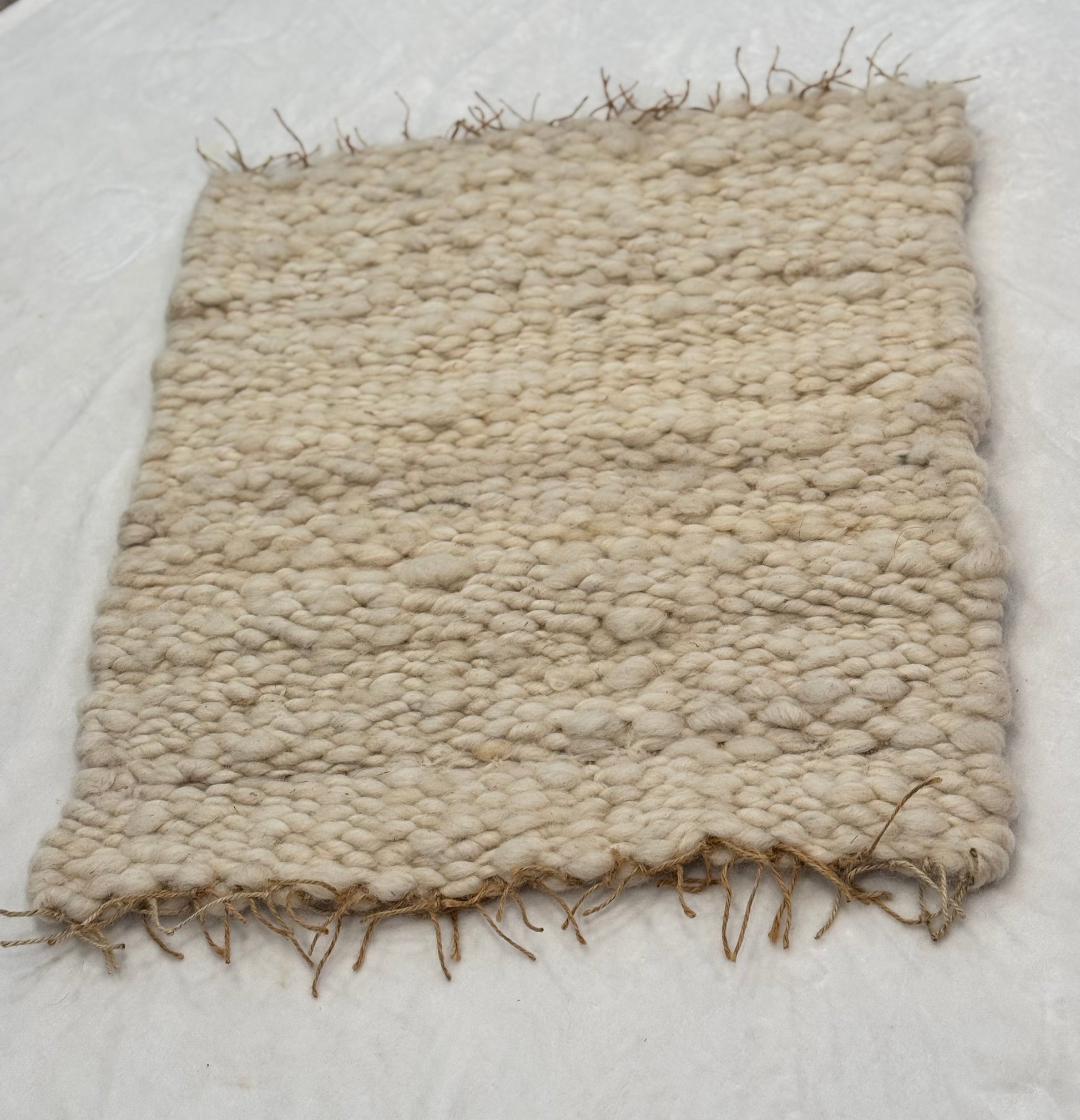 This beautiful hand woven, off white, sheep wool rug is made from 100% sheep wool grown right here at Wild Daisy Homestead.   
The warp and trim are made with 100% natural jute string.  Created on a peg loom this 23X26 rug is tightly woven together. When removed,  the finishing touches by tying the trim and hand stitching of the 100% leather tag attached, complete the project.  