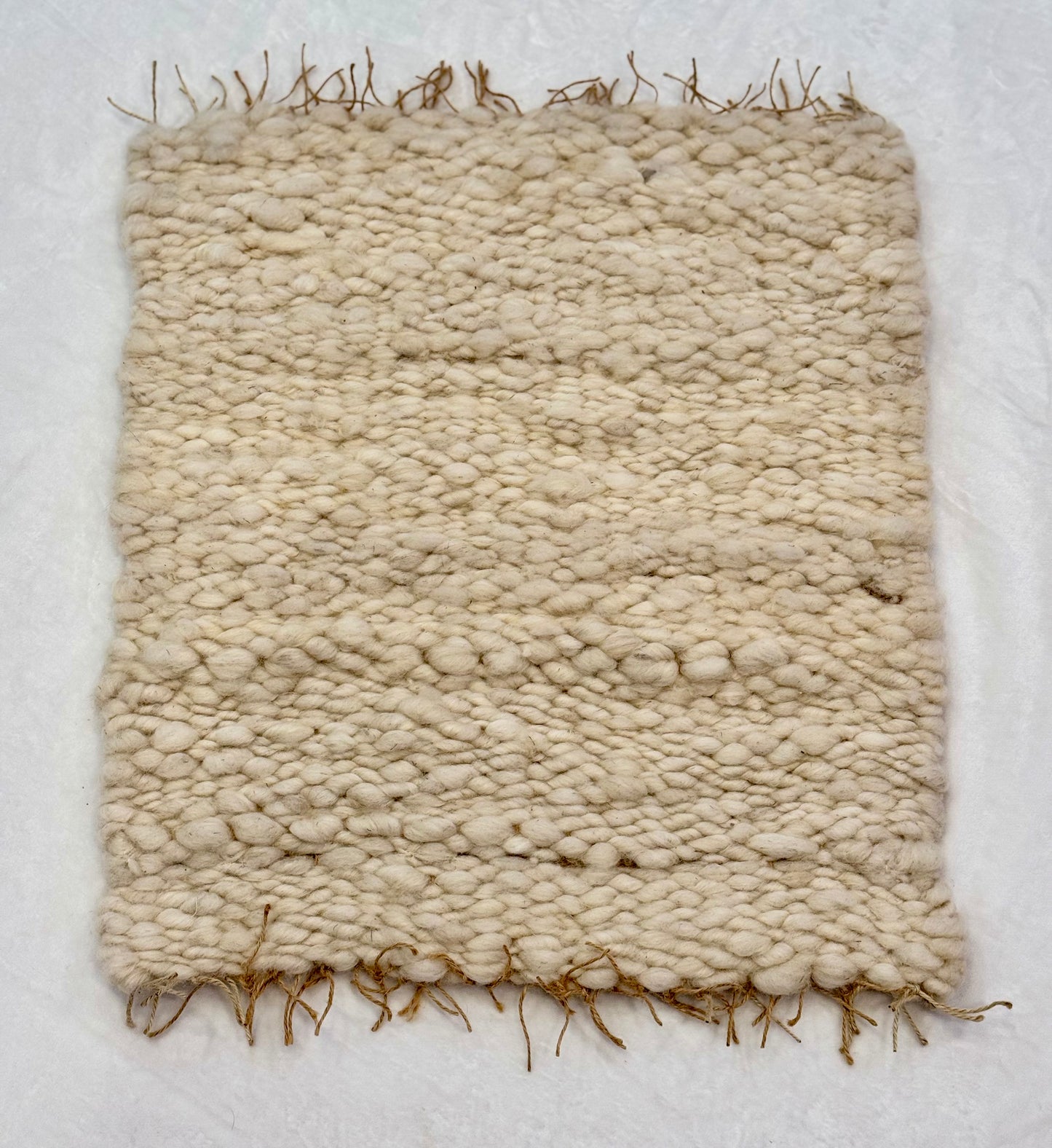 This beautiful hand woven, off white, sheep wool rug is made from 100% sheep wool grown right here at Wild Daisy Homestead.   
The warp and trim are made with 100% natural jute string.  Created on a peg loom this 23X26 rug is tightly woven together. When removed,  the finishing touches by tying the trim and hand stitching of the 100% leather tag attached, complete the project.  