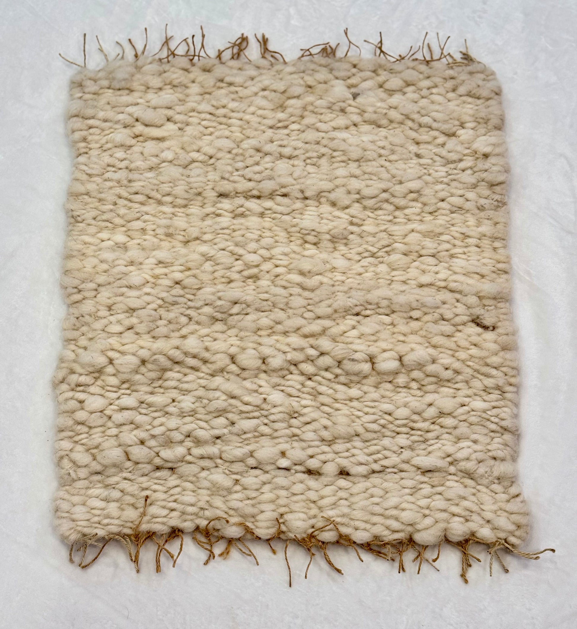 This beautiful hand woven, off white, sheep wool rug is made from 100% sheep wool grown right here at Wild Daisy Homestead.   
The warp and trim are made with 100% natural jute string.  Created on a peg loom this 23X26 rug is tightly woven together. When removed,  the finishing touches by tying the trim and hand stitching of the 100% leather tag attached, complete the project.  