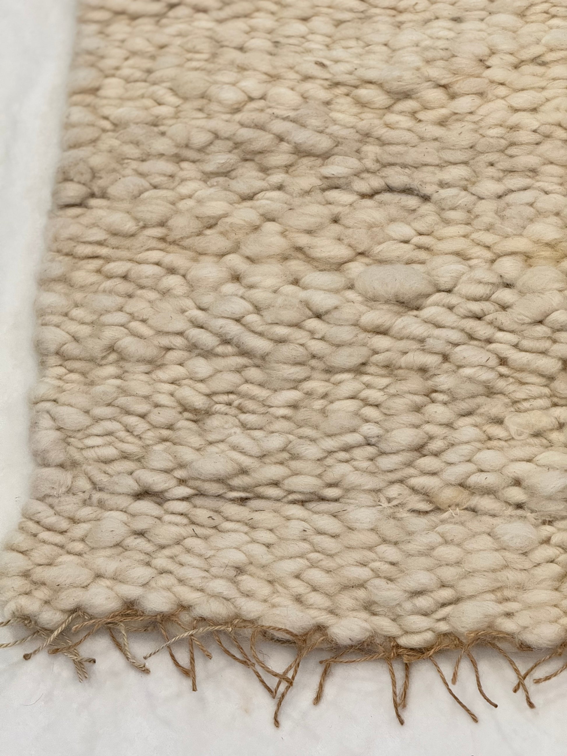 This beautiful hand woven, off white, sheep wool rug is made from 100% sheep wool grown right here at Wild Daisy Homestead.   
The warp and trim are made with 100% natural jute string.  Created on a peg loom this 23X26 rug is tightly woven together. When removed,  the finishing touches by tying the trim and hand stitching of the 100% leather tag attached, complete the project.  